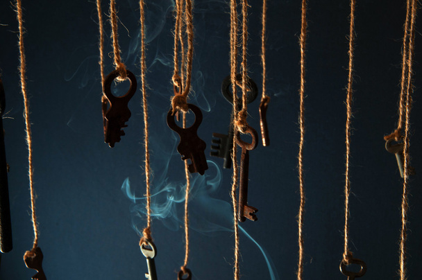 Keys hanging on a string. Smoke background. Selective focus - 写真・画像