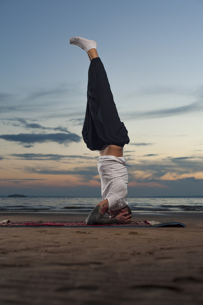 Young tattoo man practicing yoga headstand pose - Фото, изображение