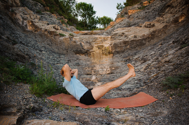 Homem saudável fazendo ioga sentado em rochas
 - Foto, Imagem