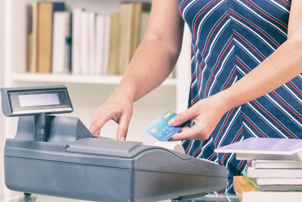 Seller at bookstore using cash register - Foto, Imagen