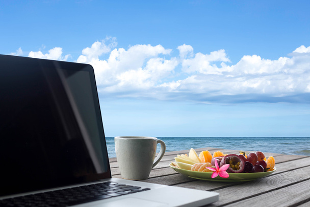 Geselecteerde focus mengt vruchten plaat en computer laptop met koffie - Foto, afbeelding