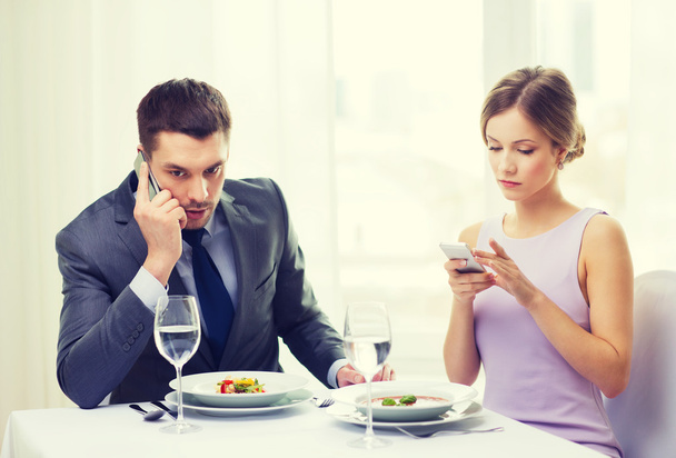 busy couple with smartphones at restaurant - 写真・画像