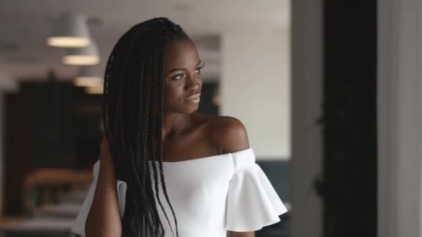 Portrait of a beautiful african american female fashion model looking to the window light while standing in dining room interior - Video