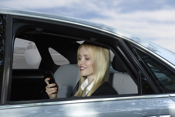 Business Woman in car with mobile phone at airport - Foto, imagen