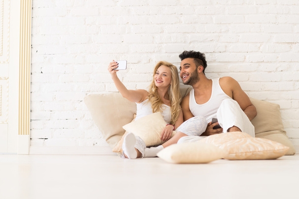 Young Couple Sit On Pillows, Girl Take Selfie Photo, Happy Smile Hispanic Man And Woman Hug Lovers - Foto, Bild
