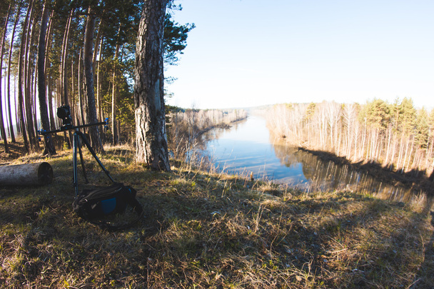 Macchina fotografica in piedi su treppiede al mattino foresta paesaggio fluviale, primavera in Urale, panoramica
 - Foto, immagini