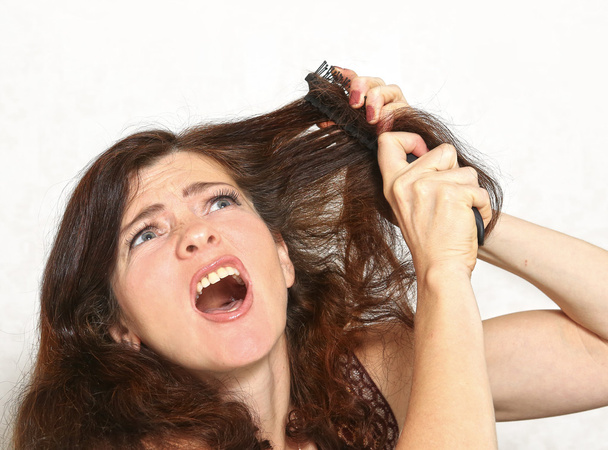 pretty young woman with brush comb stuck in hair - Photo, Image