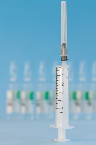 Five ml syringe on a blue background. - Photo, Image