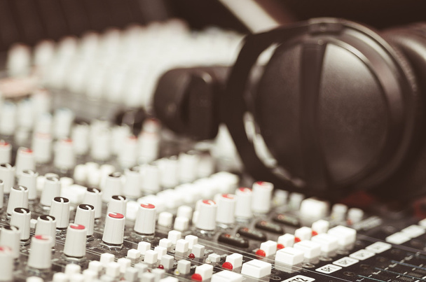 Closeup mixing console with headphones on top, faders and knobs background, artistic studio equipment concept - Fotó, kép
