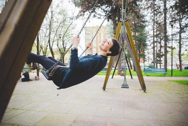 mujer divirtiéndose en un balancín en el patio de recreo
 - Foto, Imagen