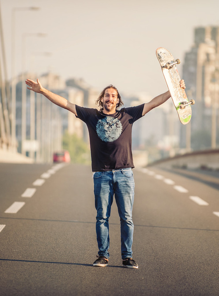 Happy skateboarder standing on the road bridge  - Fotografie, Obrázek