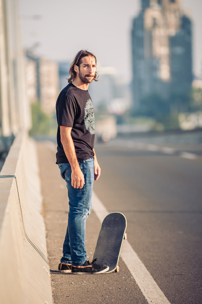 Skateboarder standing on the city road bridge - Foto, Imagem