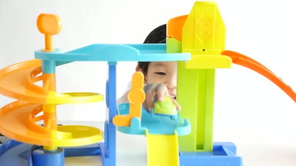 Lindo niño asiático jugando coches de juguete sobre fondo blanco, cámara lenta
 - Metraje, vídeo