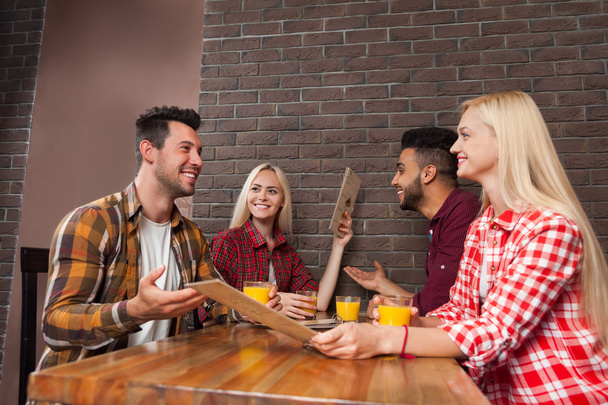 Группа молодых людей сидит за столом бар держать меню, наведение порядка, смешать расовые мужчины и женщины
 - Фото, изображение