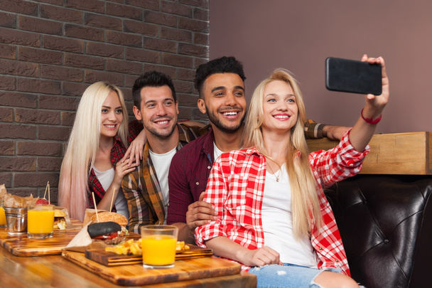 People Group Eating Fast Food Burgers Potato Sitting At Wooden Table In Cafe Taking Selfie Photo - Photo, Image