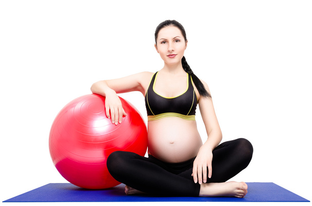 Retrato de una joven hermosa embarazada, sentada en una esterilla de yoga con fitball
 - Foto, imagen