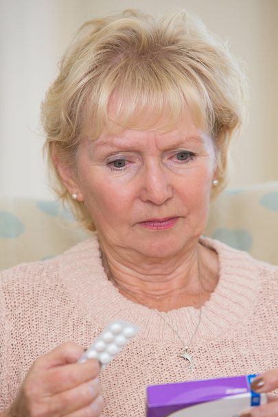 Concerned Senior Woman Reading Information On Medicine Packet - Foto, imagen