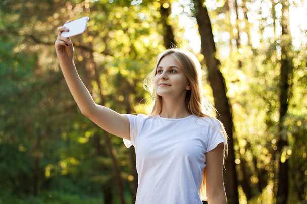 Mooi meisje doet selfie in het Park op de natuur. Gelukkig meisje. - Foto, afbeelding
