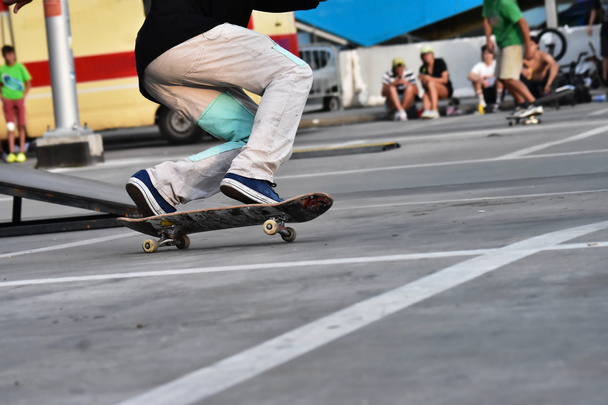 Skateboarding as extreme and fun sport. Skateboarder doing a trick in a city skate park. - Photo, Image