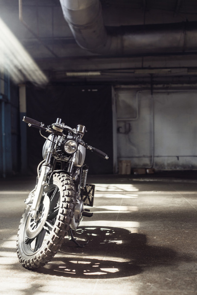 motorcycle standing in dark building in rays of sunlight - Φωτογραφία, εικόνα