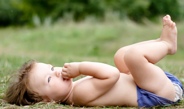 Bébé en couches couché sur le dos sur l'herbe
 - Photo, image