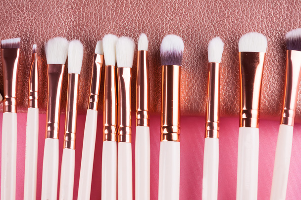 Cepillos de maquillaje facial sobre fondo rosa y marrón
. - Foto, Imagen