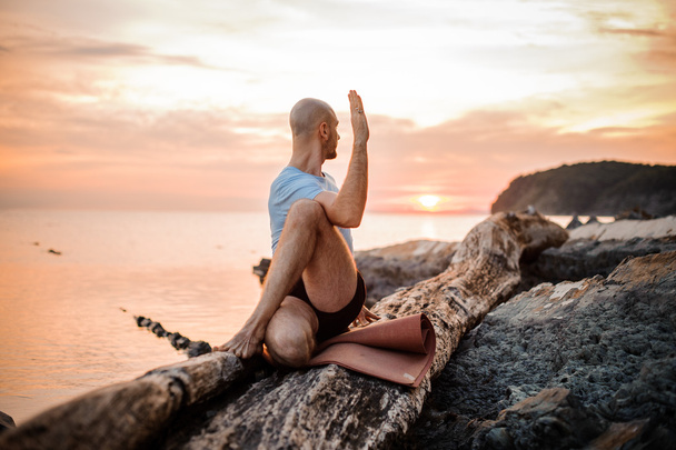 Homem sentado fazendo ioga na costa do oceano
, - Foto, Imagem