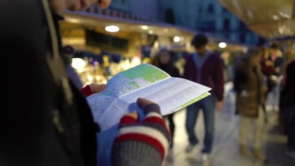 Utazó Várostérkép tartja kezében, nézi a ajándéküzletek, útvonal ellenőrzése - Felvétel, videó