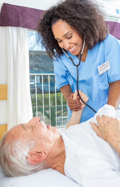 Homem idoso aposentado assistido por enfermeira na clínica de reabilitação
 - Foto, Imagem