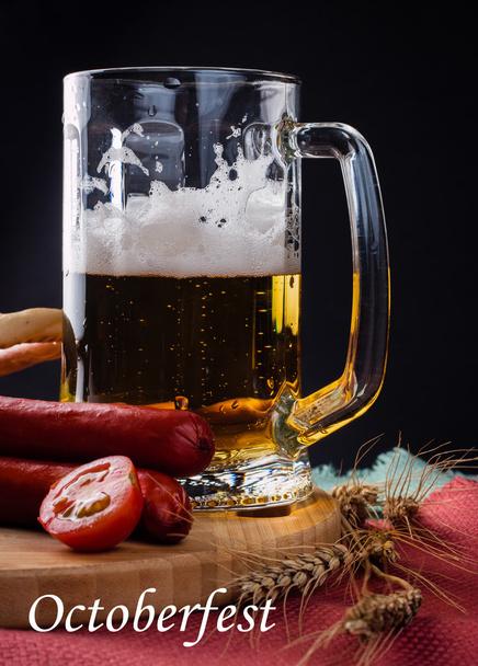 Vaso de cerveza ligera, embutidos de carne y tomates sobre tabla de madera
 - Foto, Imagen