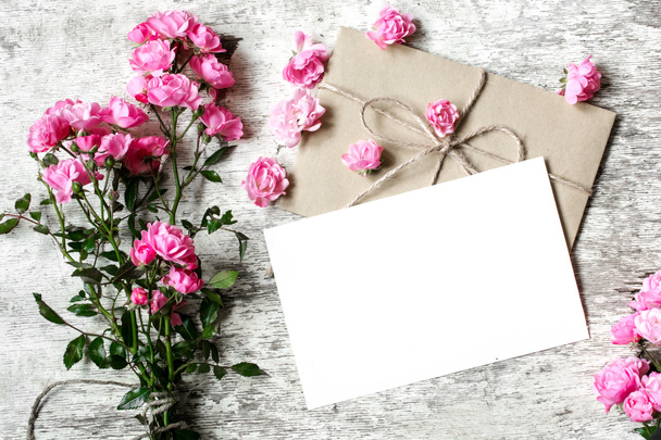 Ramo de rosas rosadas tiernas con una tarjeta de felicitación en blanco y sobre
 - Foto, imagen