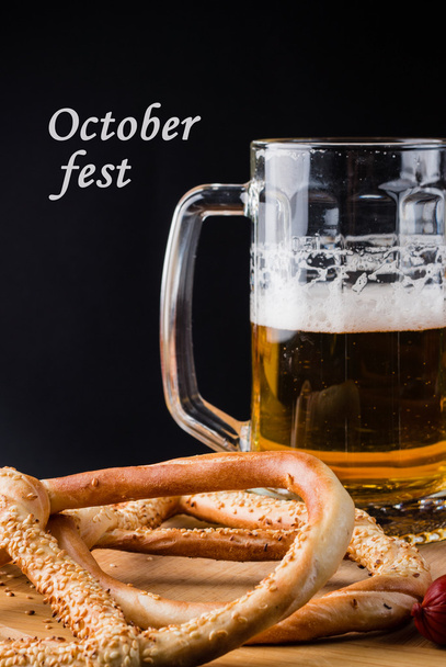 Стакан пива, крендель на деревянной доске с текстом Octoberfest
 - Фото, изображение