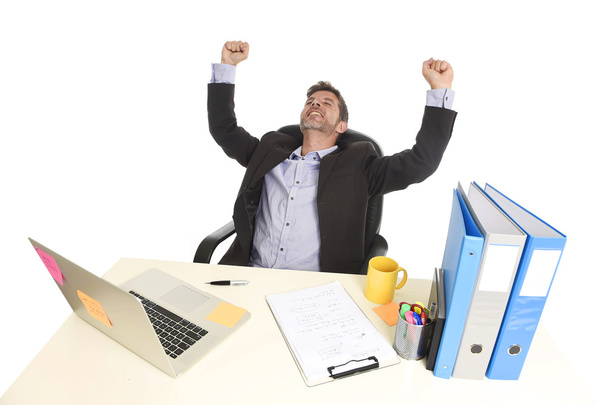 joven atractivo hombre de negocios feliz haciendo puño signo de la victoria sentado en escritorio de la computadora de la oficina celebrando
 - Foto, imagen