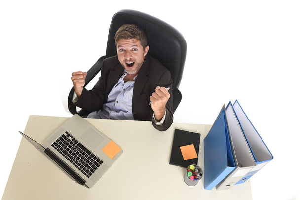atractivo hombre de negocios feliz haciendo signo de victoria sentado en escritorio de la computadora de la oficina celebrando
 - Foto, Imagen