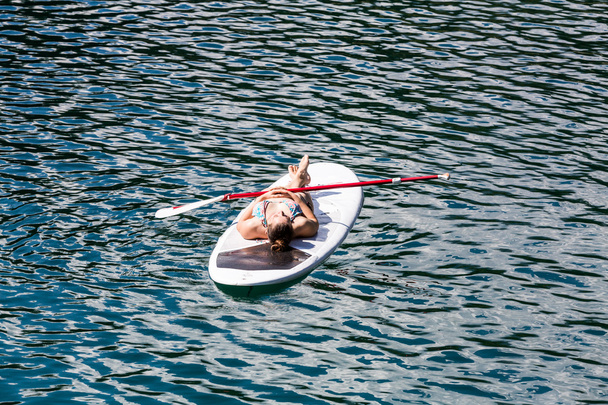 Girl laying on a paddleboard on the Caumasee in Switzerland - 写真・画像