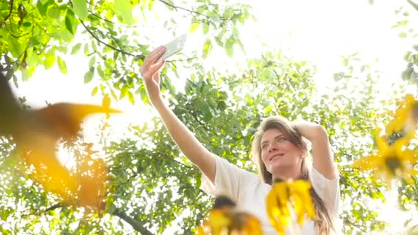 Kaunis tyttö tekee selfie keskuudessa auringonkukat
. - Materiaali, video