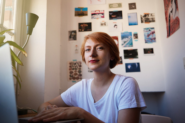 One Modern Female Coworker Smiling During Working Process.Young Hipster  Startup Project.Woman short hair and white tshirt typing computer morning light. Productive job concept comfy place. - Φωτογραφία, εικόνα