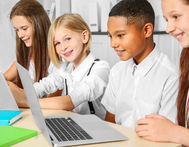 Koululaiset, jotka istuvat luokkahuoneessa kannettavan tietokoneen ja tablettien kanssa
 - Valokuva, kuva