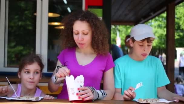 Matka a děti na kolečkových bruslích jíst  - Záběry, video