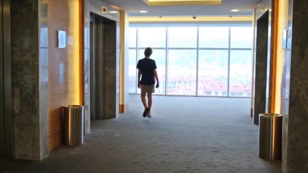 boy going in hall with doors of lifts - Footage, Video