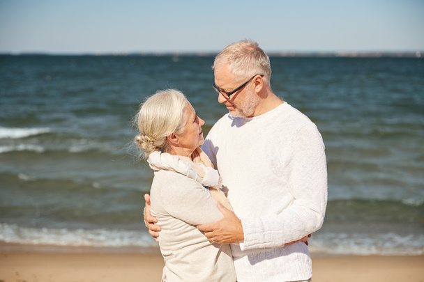 счастливая пожилая пара обнимается на летнем пляже
 - Фото, изображение
