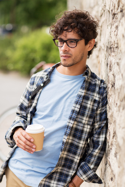 man in eyeglasses drinking coffee over street wall - Zdjęcie, obraz