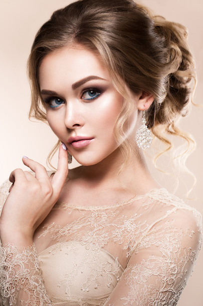 Beautiful bride with fashion wedding hairstyle - on beige background. - Photo, Image