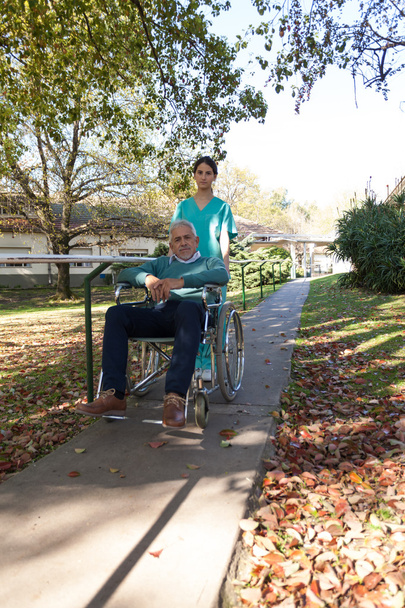 Медсестра, що носить пацієнта в інвалідному візку в парку
 - Фото, зображення
