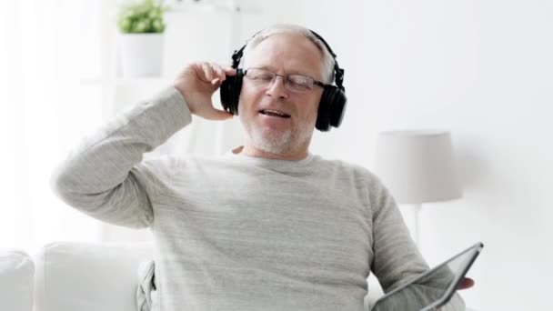 senior man with tablet pc and headphones at home 121 - Felvétel, videó