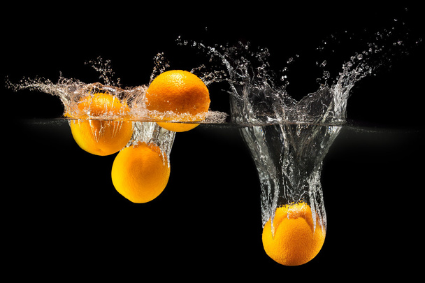 Group of fresh fruits falling in water with splash on black background - Fotografie, Obrázek