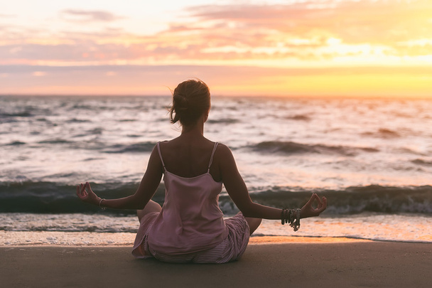 mladá žena cvičí jógu na oceán písečné pláži při západu slunce - Fotografie, Obrázek
