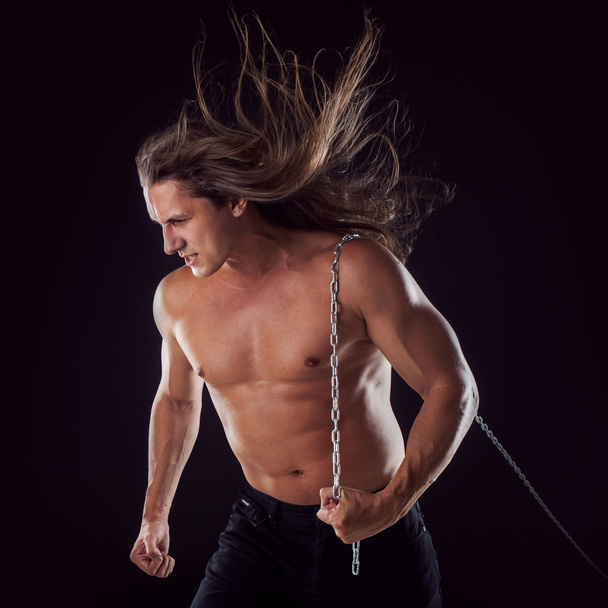 Young man with long hair dragging something behind him. Strong. - Foto, afbeelding