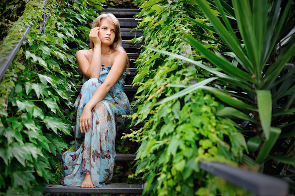 Nuori tyttö istuu portaissa puutarhassa peitetty muratti
 - Valokuva, kuva