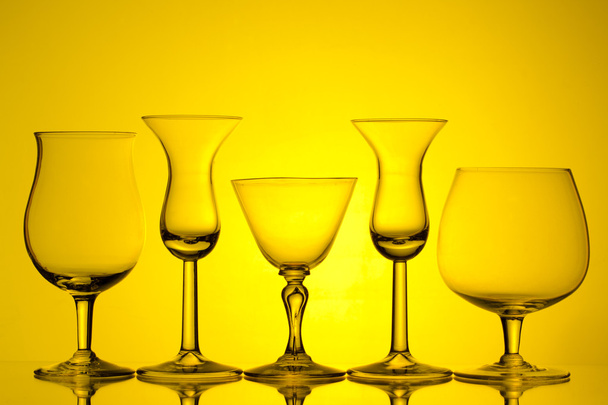 silhouet van wijnglazen op gele achtergrond - Foto, afbeelding